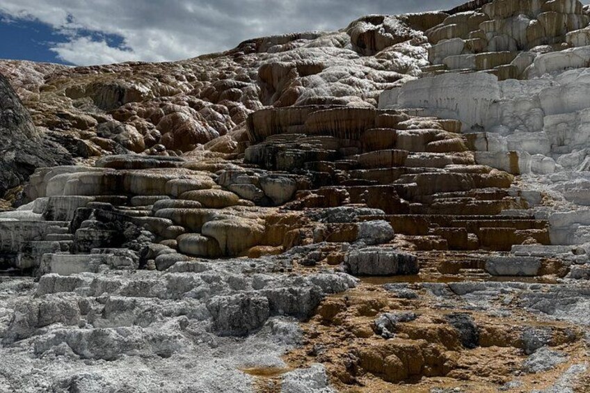 Stufenförmige Mineralformationen mit unterschiedlichen Farben und Strukturen, vermutlich eine natürliche geologische Sehenswürdigkeit. 2
