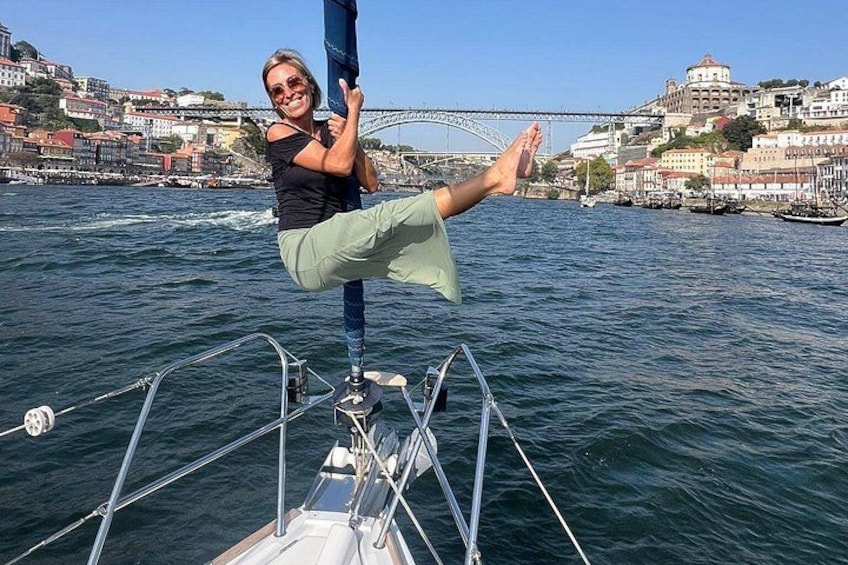 A person on a sailboat with a cityscape and bridge in the background. 2