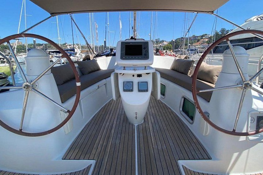 A boat deck with a steering wheel, control panel, and cushioned seating. 3
