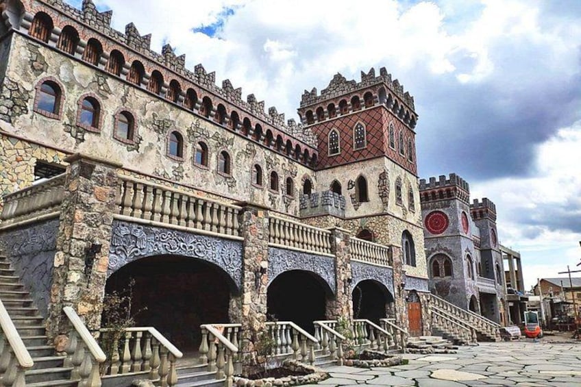 A historic building with arched doorways, a clock tower, and a staircase leading to an upper level. 2