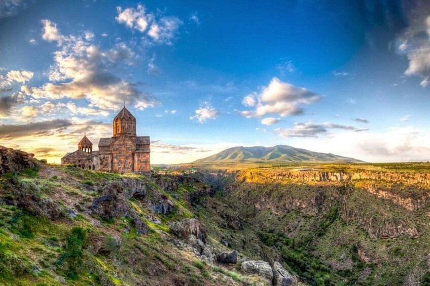 A historic church on a hill, a mountainous landscape, and a clear sky. 5