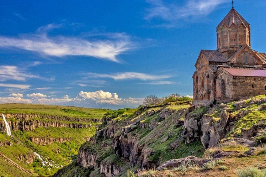 A historic stone church on a hillside with a clear sky. 4