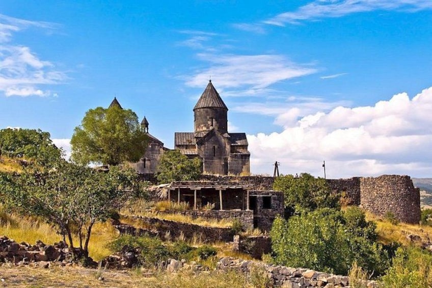 An old stone building with a bell tower, surrounded by trees and dry grass. 3