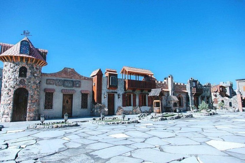Una plaza histórica con edificios de piedra, una torre y un cielo azul despejado. 4