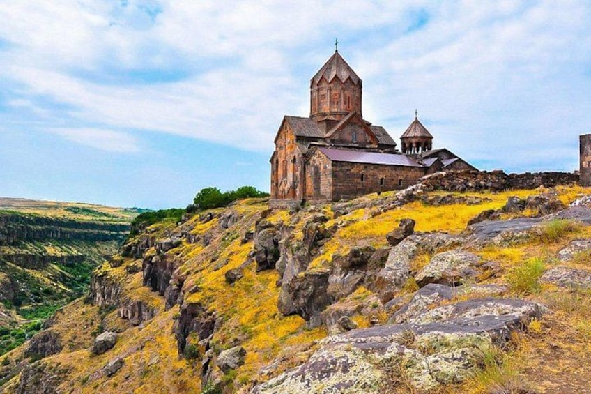 A historic church on a hill with rocky terrain and a valley in the background. 4