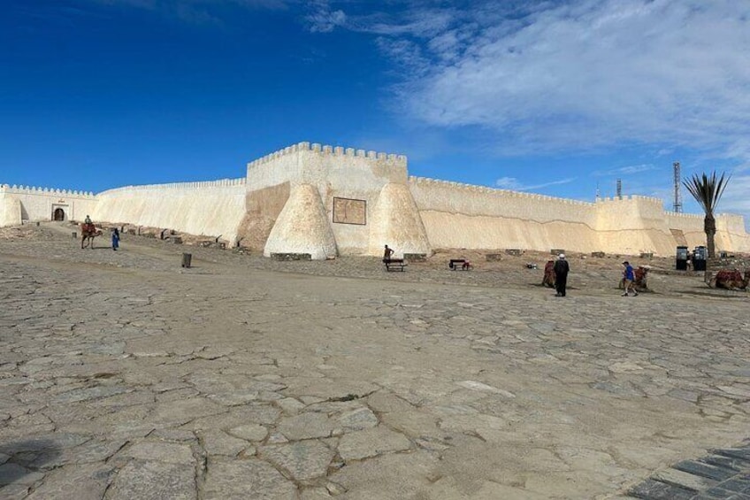 En historisk fästning med ett stort, centralt placerat torn, en stenlagd innergård och en klarblå himmel. 4
