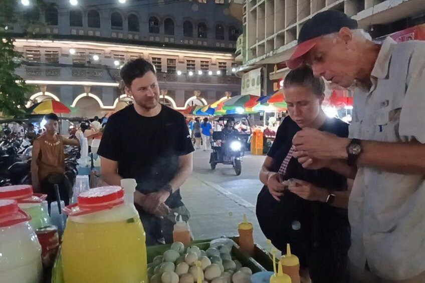 A street market with food stalls, people, and a building in the background. 3