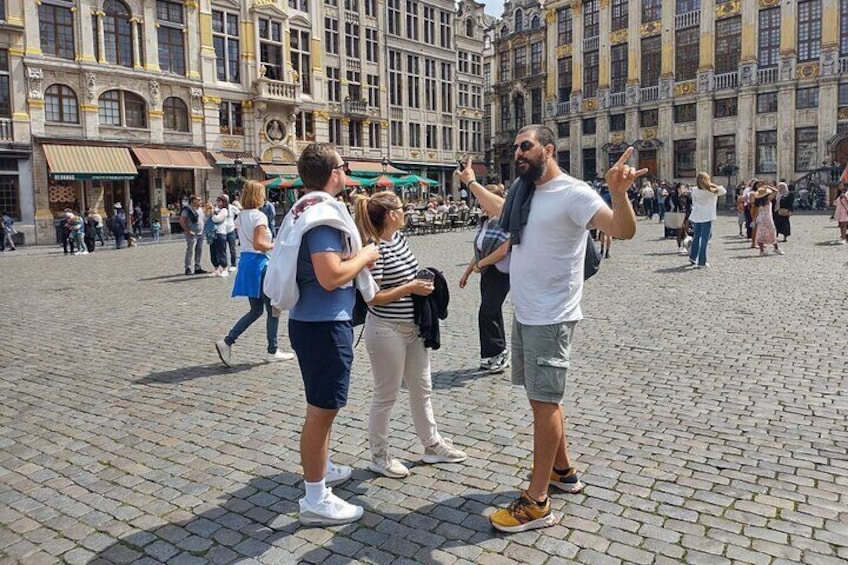 A group of people in a cobblestone square with historic buildings in the background. 3