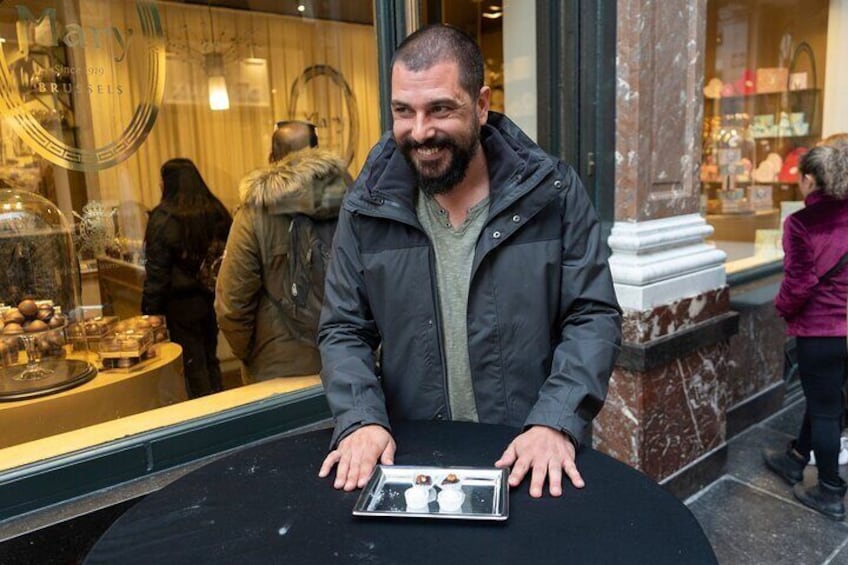 A man sitting at a table with a box of chocolates in front of him. 5