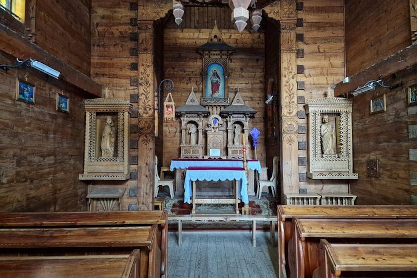 Un interno in legno con un altare centrale, icone religiose incorniciate e panche. 2