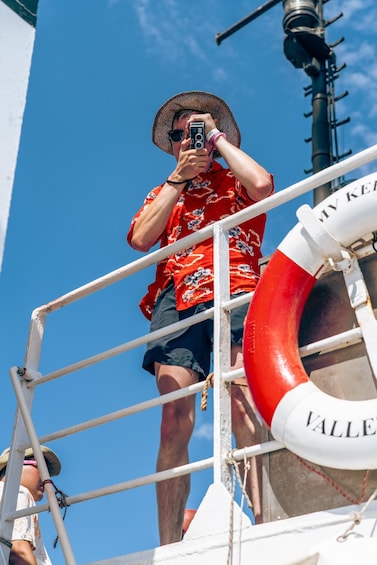 A person taking a photo with a camera on a boat deck. 5