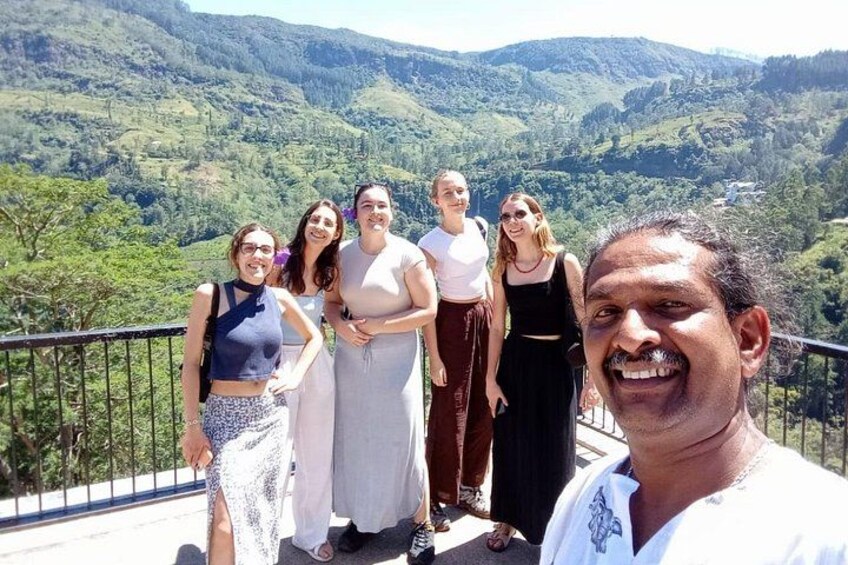A group of people standing on a balcony with a mountainous landscape in the background. 4