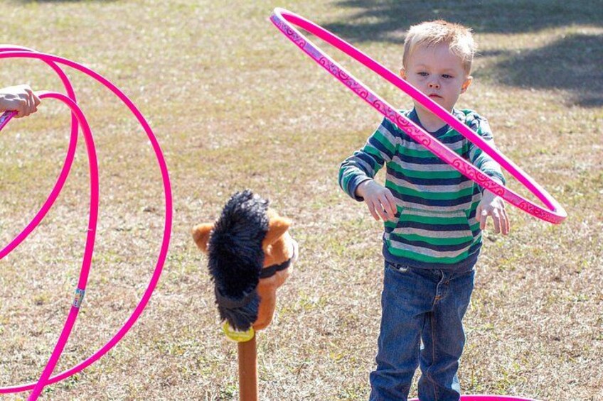 Un niño jugando con un aro de hula y un peluche en un campo cubierto de césped. 3