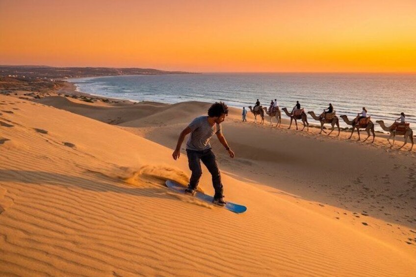 Une personne qui fait de la planche à neige en descendant une dune de sable au coucher du soleil. 1