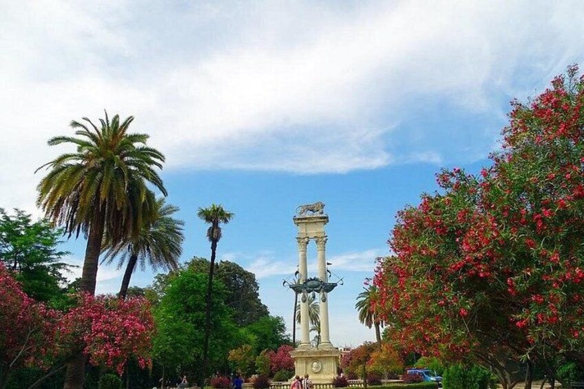 A park with a central monument, palm trees, and flowering trees. 4