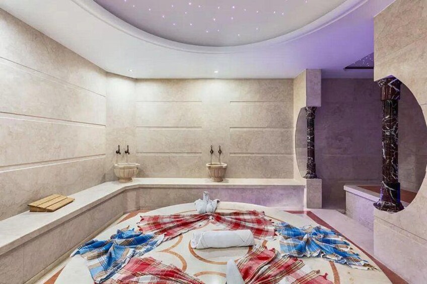 Un spa moderno con una bañera grande, paredes de mármol y una alfombra decorativa. 3