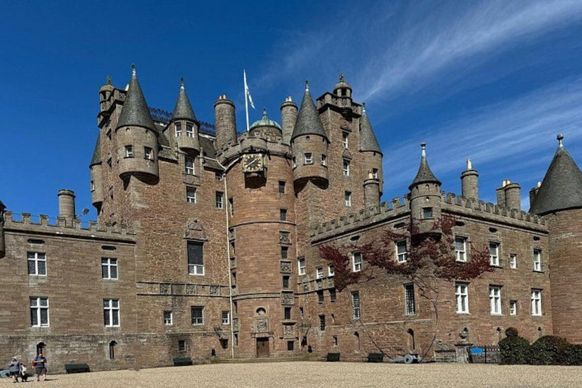 A large, historic castle with multiple towers and turrets, surrounded by a well-maintained lawn. 5