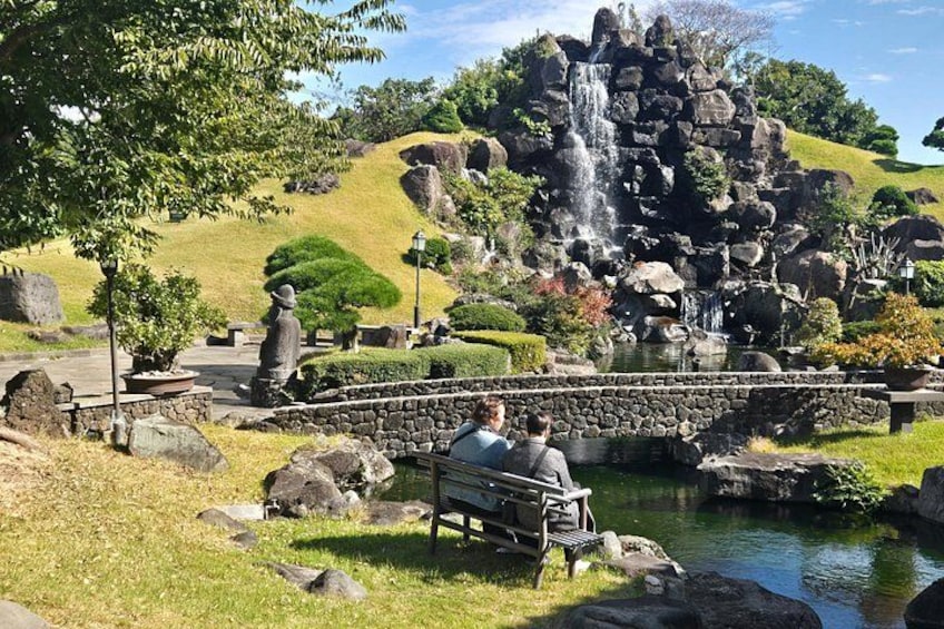 Une cascade, un pont de pierre, un étang et une statue dans un parc. 5