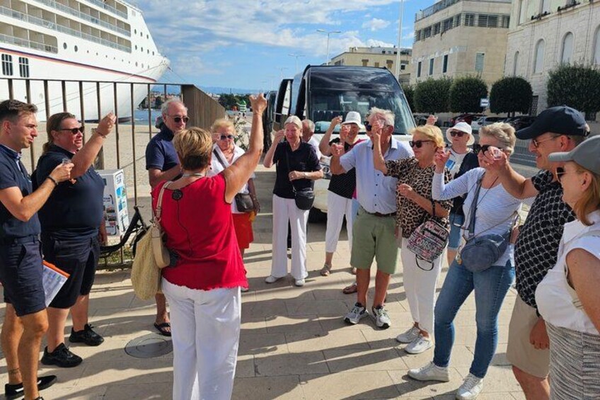 Un grupo de personas en una acera, algunas levantando las manos, cerca de un crucero y un autobús. 2