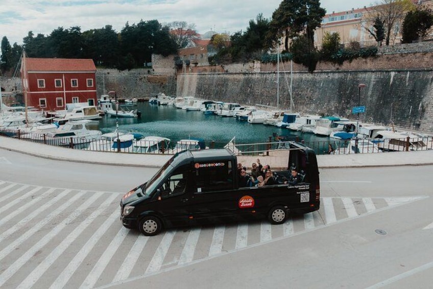 Una camioneta negra estacionada en una carretera con un puerto deportivo al fondo. 3