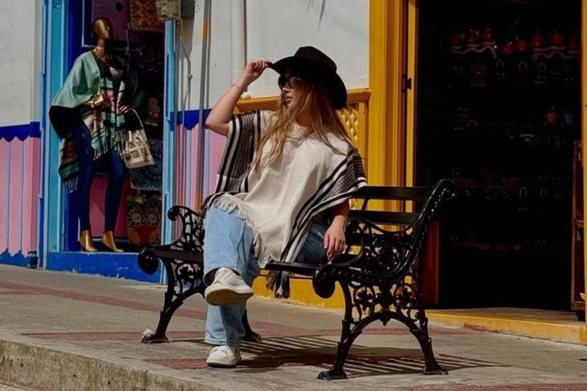 Una persona sentada en un banco en un entorno al aire libre con un edificio al fondo. 2