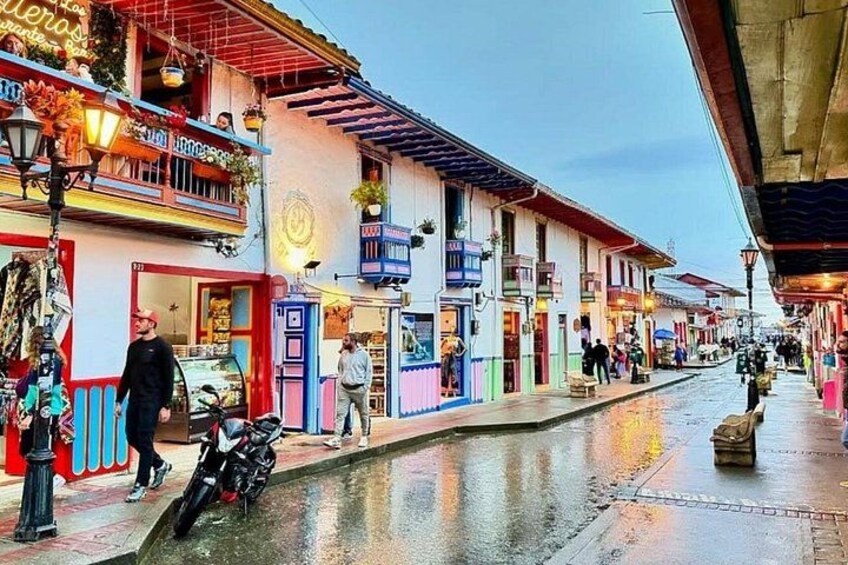 Una calle con tiendas y una motocicleta estacionada al costado. 4