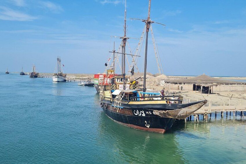 A traditional sailing ship docked at a harbor with other boats in the background. 5