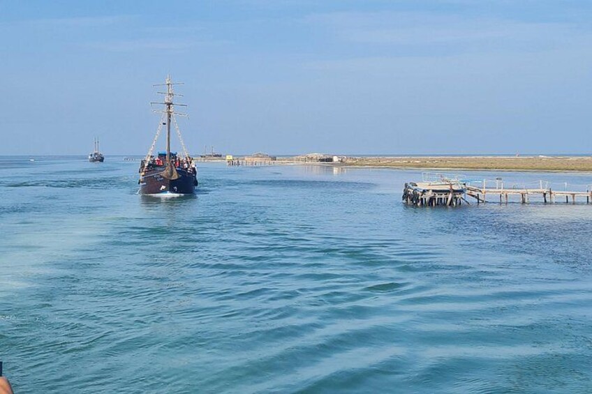 A large ship sailing near a pier, calm water, and a distant shoreline. 3