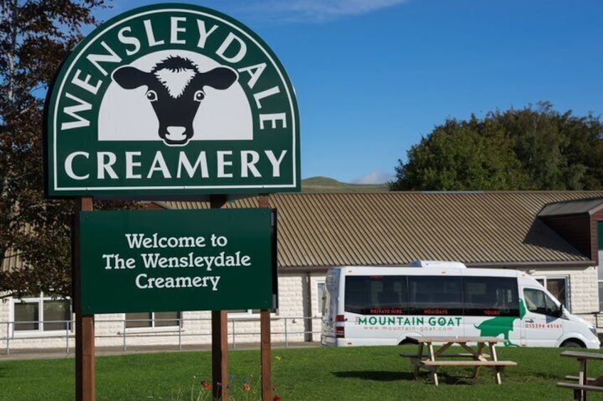 A creamery sign with a cow logo, a welcome sign, and a parked van. 3