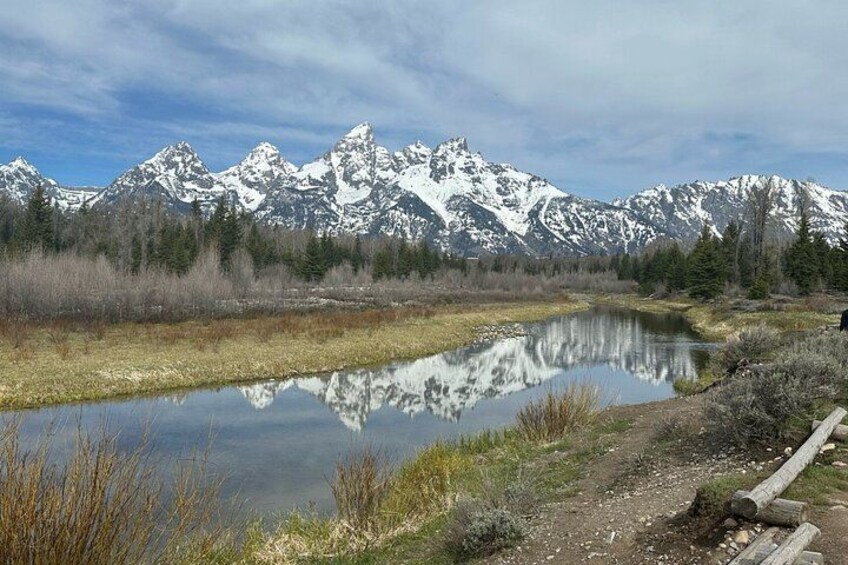 A mountain range with snow-capped peaks, a calm lake reflecting the scenery, and a dirt path leading through the landscape. 3