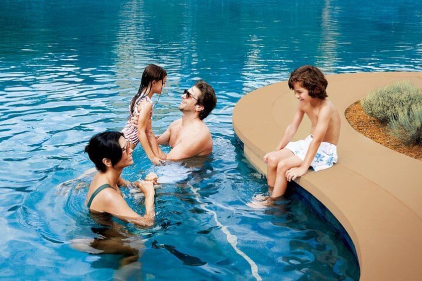 A swimming pool with people in the water and on the edge. 5