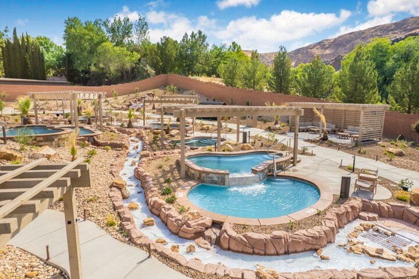 A hot tub area with multiple hot tubs, a small waterfall feature, and a pool. 1