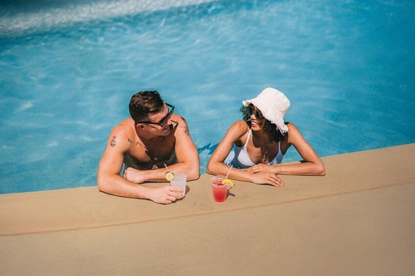 Two people sitting by a pool with drinks. 5