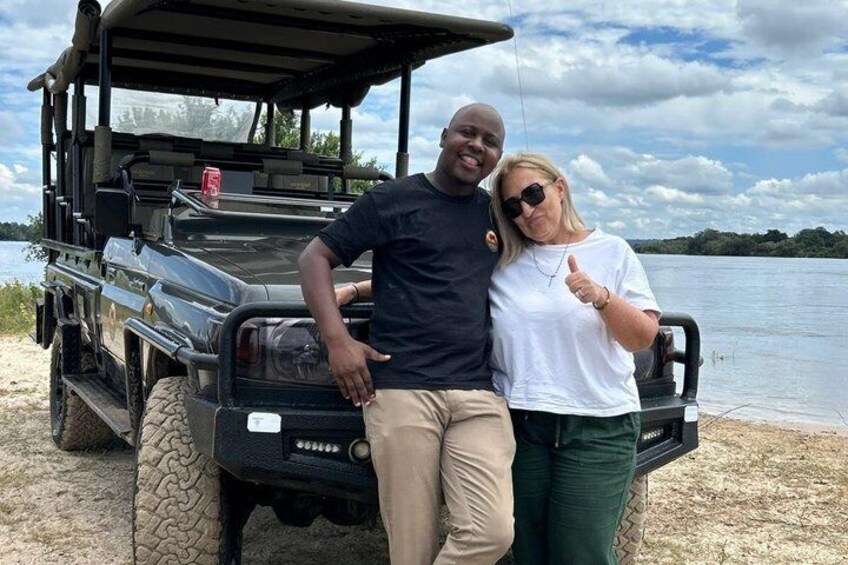 A vehicle parked by a lake with a person leaning on it. 2