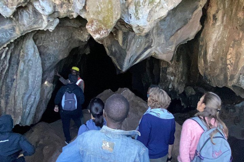 A group of people entering a cave with rocky walls. 2