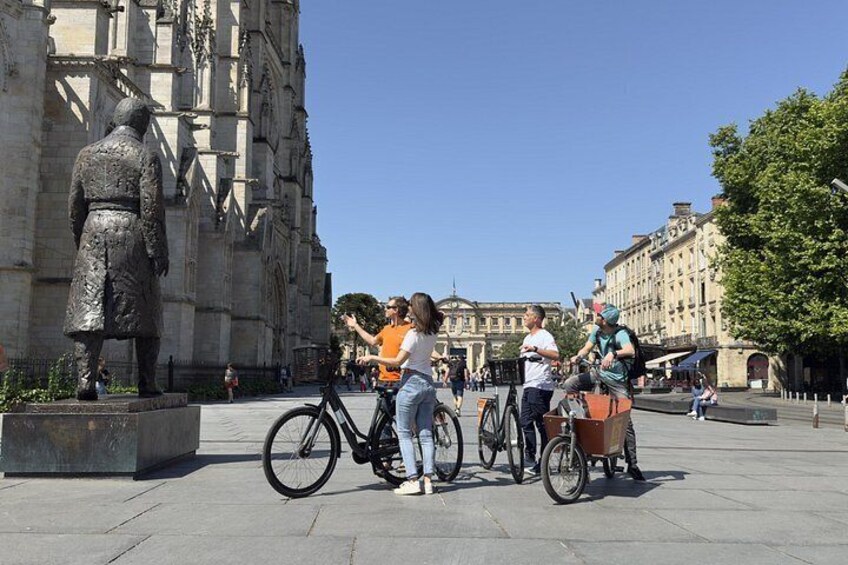 Una estatua, una bicicleta y gente en una plaza pública. 2