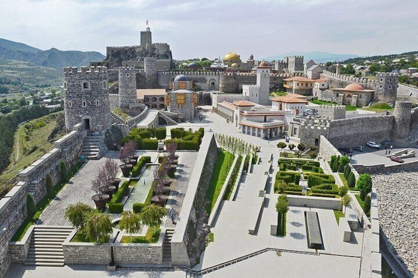A historic fortified town with a castle, a church, and a well-maintained garden. 2