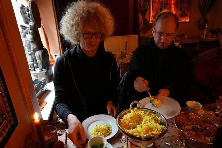 Two people dining at a table with various dishes, including rice and a bowl of soup. 3