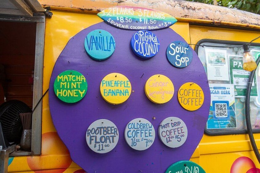 A colorful food truck with various drink options displayed on a circular sign. 4