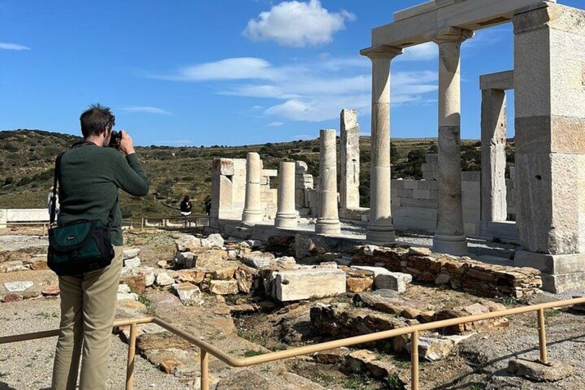 Ancient ruins with columns and a person taking a photo. 1