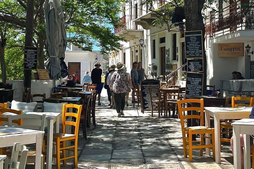 Une rue pavée avec des terrasses, des tables et des chaises, et des gens qui se promènent. 5