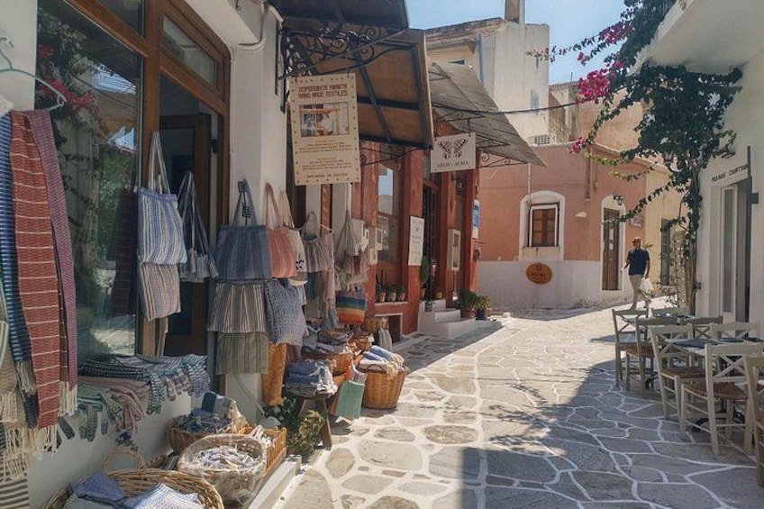Una calle estrecha con tiendas, mesas al aire libre y bolsas colgantes. 3