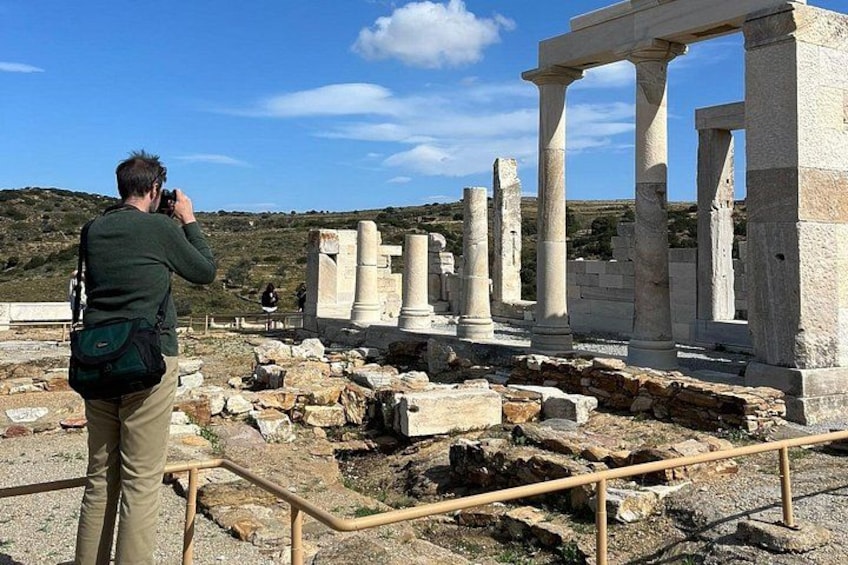 Des ruines antiques avec des colonnes, une personne prenant une photo et un ciel dégagé. 1