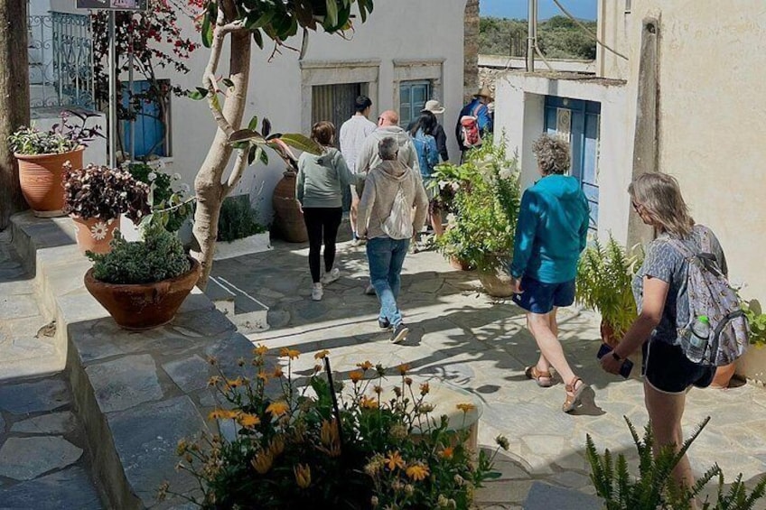 A group of people walking in a courtyard with potted plants and a tree. 2