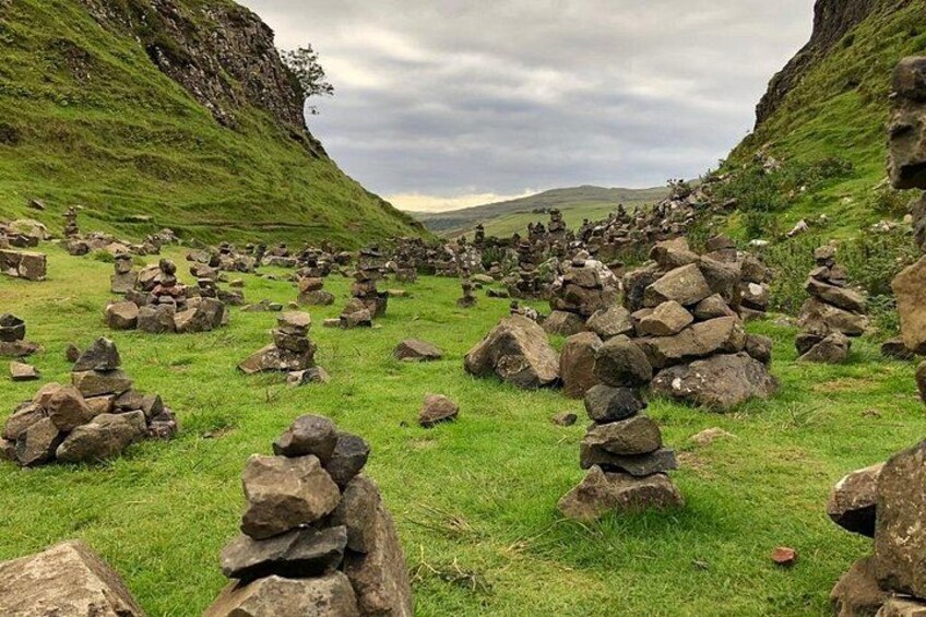 A landscape with numerous stone cairns and grassy terrain. 2