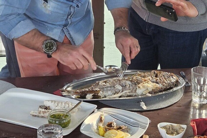 Deux personnes sont assises à une table et dégustent des plats de fruits de mer, accompagnés d'un verre d'eau et de divers condiments. 5