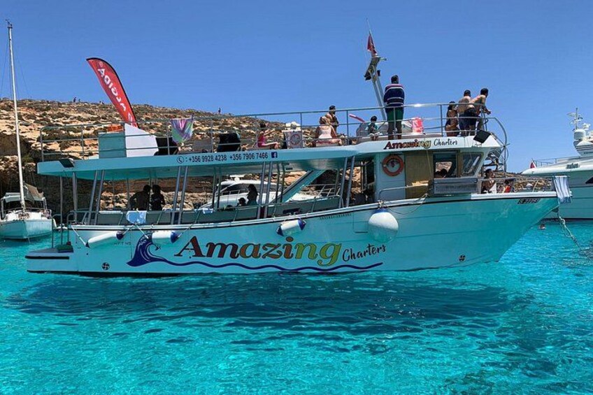 A boat named 'Amazing Charters' with people on board, anchored near rocky cliffs. 4