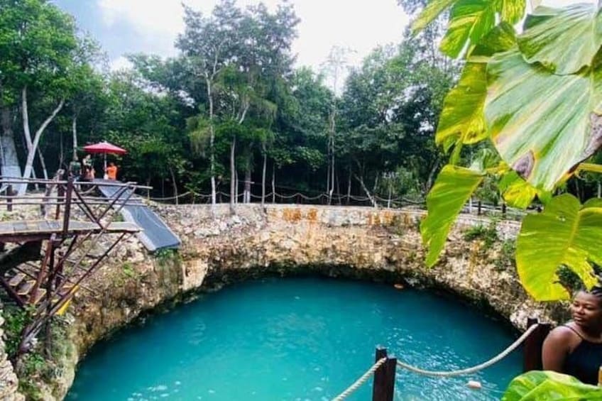 Une piscine naturelle entourée d’arbres et une plateforme en bois délimitée par une barrière en corde. 5