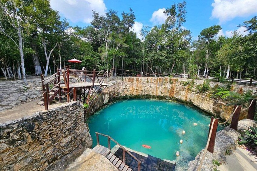 Une piscine naturelle entourée d’arbres et une terrasse en bois avec un parasol rouge. 1