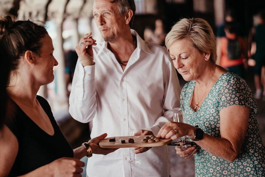 A group of people at a social gathering, possibly a party or event, with a wooden board game in the center. 2